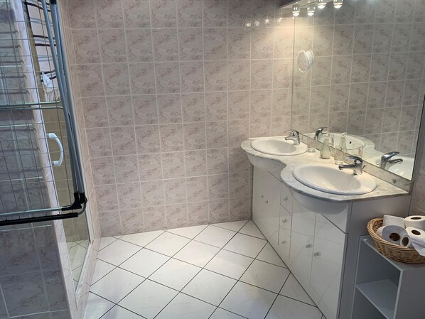Un baño moderno con dos lavamanos, un espejo grande y una zona de ducha.