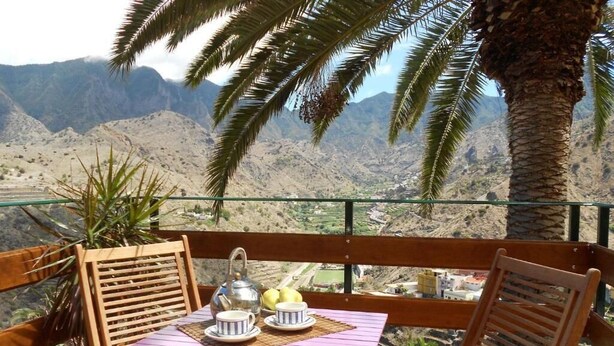 Eine Holzterrasse mit Tisch für zwei Personen, mit Blick auf eine Berglandschaft.