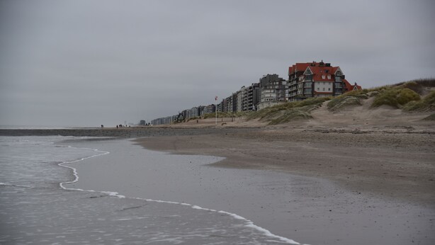 Una playa con una hilera de edificios de varios pisos, incluyendo una estructura destacada de techo rojo.
