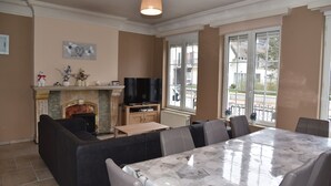 Amplia sala de estar con chimenea, televisor y comedor con mesa y sillas.