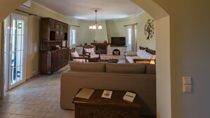 A spacious living room with a fireplace, a television, and a large window. - It is our pleasure to welcome you to Kefalonia Island and invite you to enjoy yo (kefalonia)