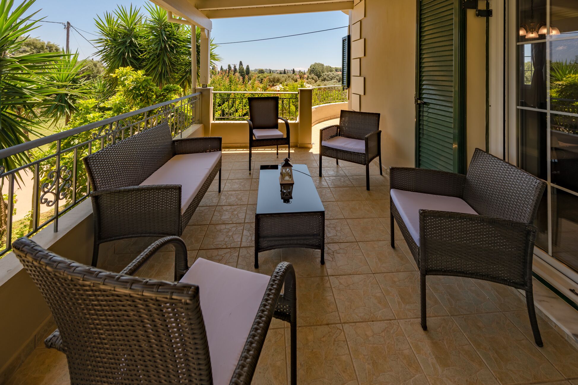 A balcony with wicker furniture, a table, and a lantern.