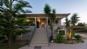 A two-story house with a staircase leading to the entrance, surrounded by palm trees and a well-maintained lawn. - It is our pleasure to welcome you to Kefalonia Island and invite you to enjoy yo (kefalonia)