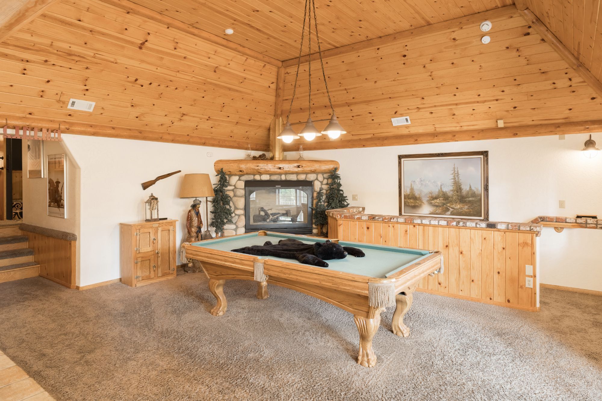 Ein Holzeinrichtung mit Billardtisch, Kamin und einem Gemälde an der Wand.