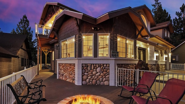 Una cabaña con chimenea de piedra, mobiliario exterior y un patio cubierto.