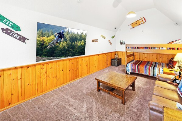 A cozy room with a wooden floor, a sofa, a table, and a bunk bed.
