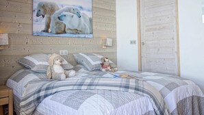 Ett sovrum med ett träpanelat tak, en stor målning av en isbjörn på väggen, en säng med ett rutigt överkast och två gosedjur på sängen.