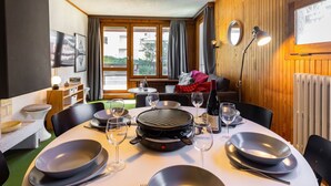 Comedor con una mesa dispuesta para dos, una parrilla y vistas al exterior a través de amplios ventanales.
