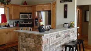 Una cucina con mobili in legno, un'isola in pietra e una ventola a soffitto.