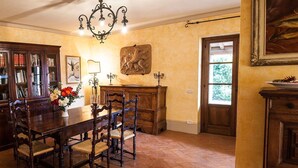 A dining area with a wooden table, chairs, a chandelier, and a bookshelf. - Cosy apartment for 6 people with WIFI, pool, TV, patio, pets allowed and panoramic view (Allerona)