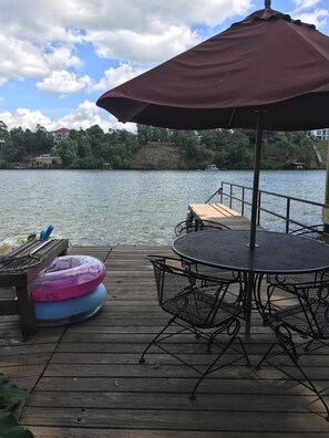 Eine Holzterrasse mit Tisch, Stühlen und einem Sonnenschirm, sowie Luftmatratzen.