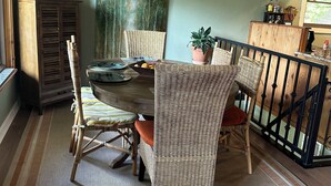 A dining area with a wooden table, wicker chairs, a hanging light fixture, and a view of the outdoors through a window. - Stan's Lake Hamilton II, MainChannel, Kayaks, Fire Pit, Swim/Boat Dock, Pontoon (Hot Springs)