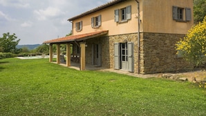 Une maison à deux étages, dotée d’une façade en pierre et d’un toit recouvert de tuiles.