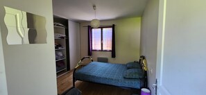 A bedroom with a bed, a wardrobe, a window with curtains, and a hanging light fixture. - House of 100 m2 on a 2500 m2 fenced (Cierp-Gaud)