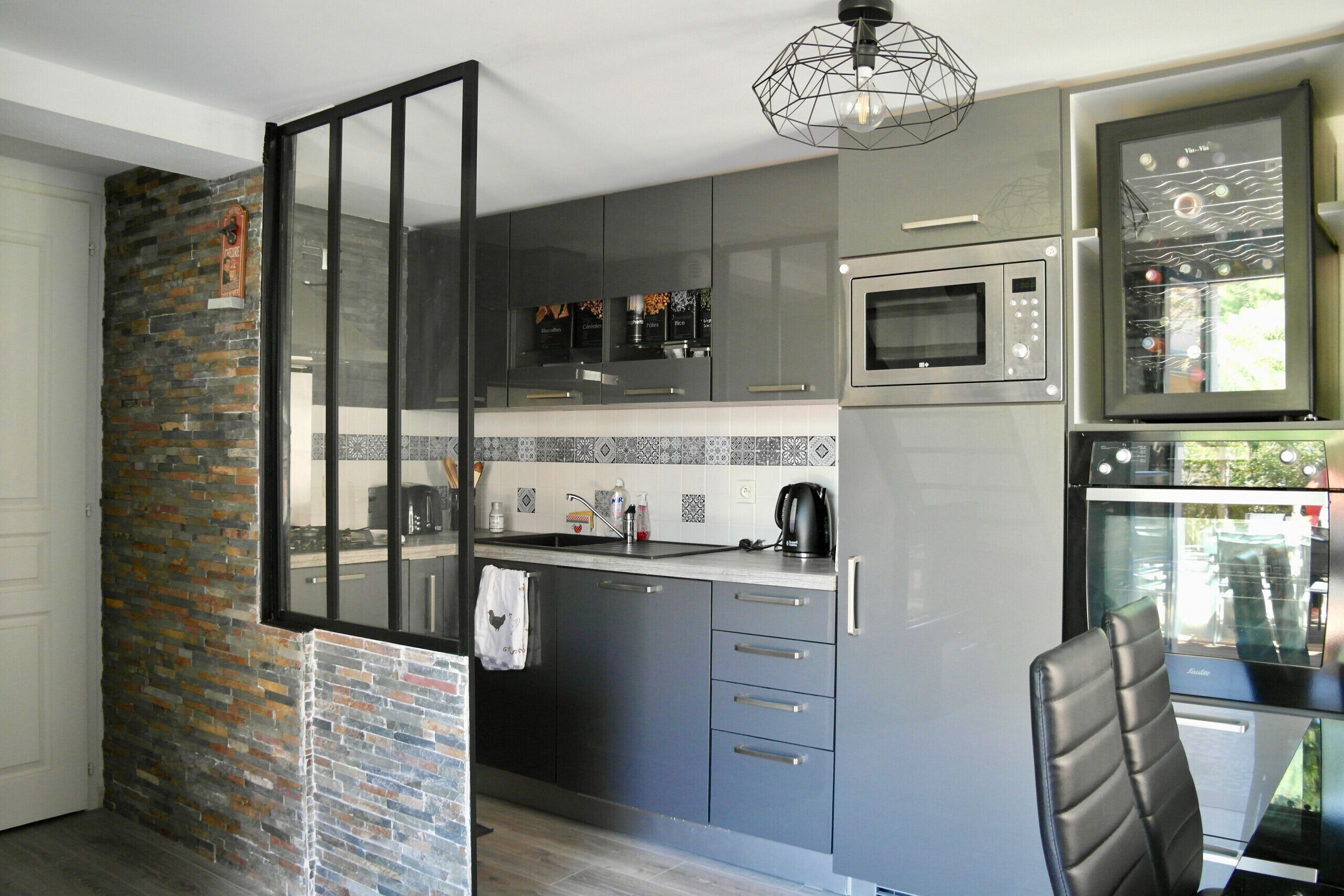 A modern kitchen with grey cabinets, a built-in microwave, and a coffee machine.