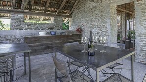 An outdoor dining area with a stone wall, wooden beams, and metal furniture. - Stunning private villa with WIFI, private pool, TV, terrace, pets allowed and panoramic view (Trezzo Tinella)