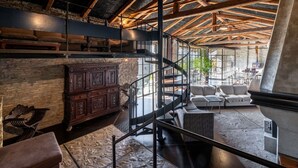 A spacious loft with exposed wooden beams, a spiral staircase, and a stone fireplace. - Stunning private villa with WIFI, private pool, TV, terrace, pets allowed and panoramic view (Trezzo Tinella)