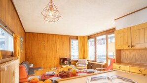 Ein gemütliches Zimmer mit Holzwänden, einem Esstisch mit Orangen, einem Buch und einem Fernseher.