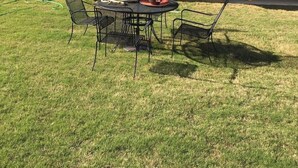 A backyard with a round table and chairs, a blue umbrella, and potted plants. - Beautiful House for the Masters (Grovetown)