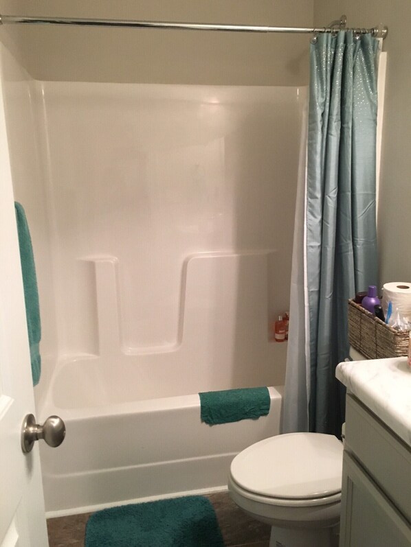 A bathroom with a bathtub, toilet, and shower curtain. - Beautiful House for the Masters (Grovetown)