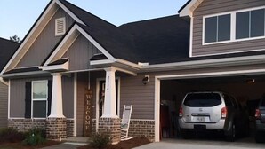 A two-story house with a garage, a front porch, and a driveway. - Beautiful House for the Masters (Grovetown)