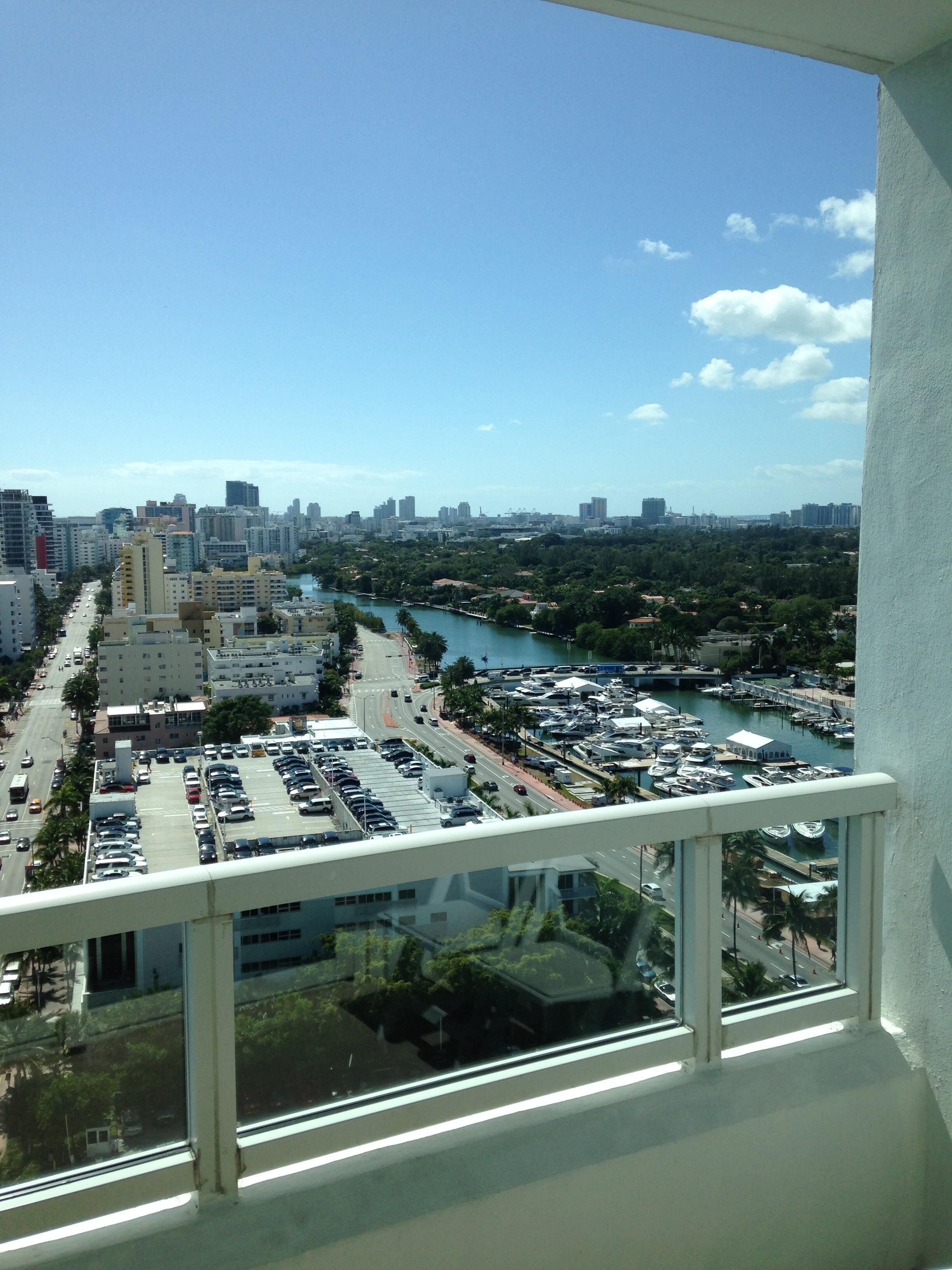 A high-rise building with a view of a marina, cityscape, and a river.