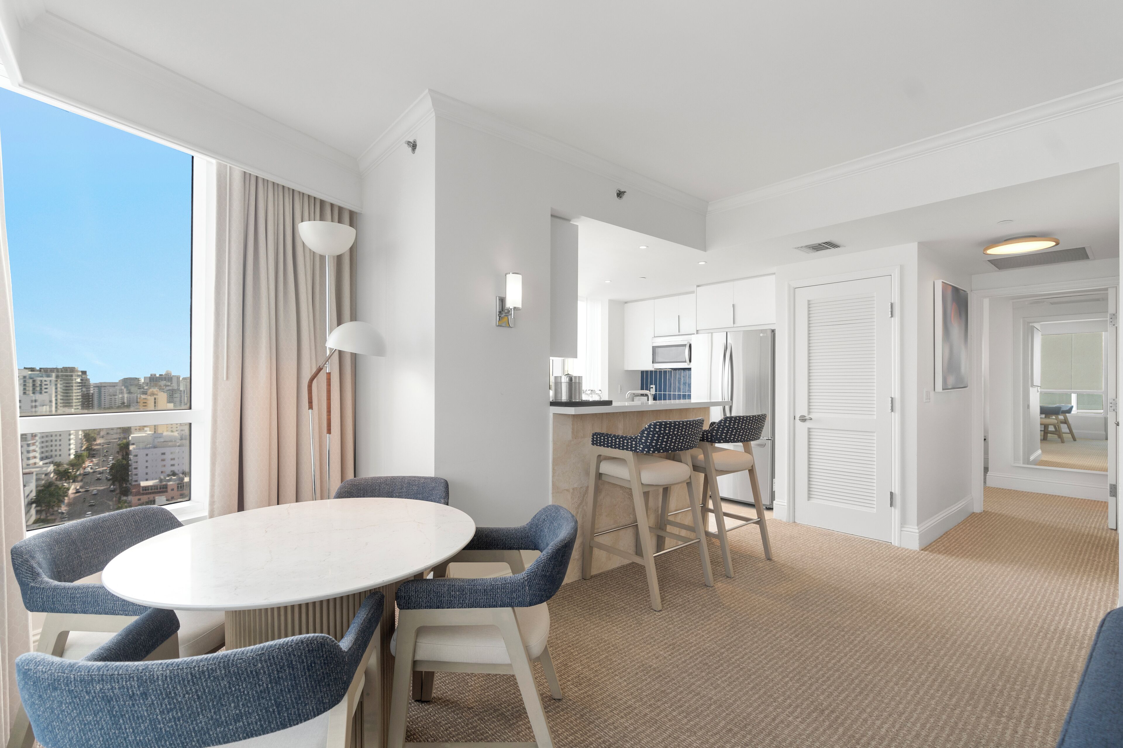 Ein modernes Hotelzimmer mit Essbereich, einer Küchenzeile und Blick auf die Stadt.