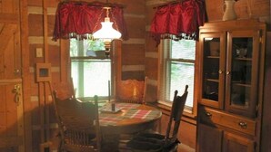 A cozy room with a wooden interior, a dining table with chairs, a cabinet, and a hanging light fixture.