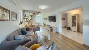 A modern living room with a sofa, coffee table, and a staircase leading to another room. - Villa Parlera (Ližnjan)