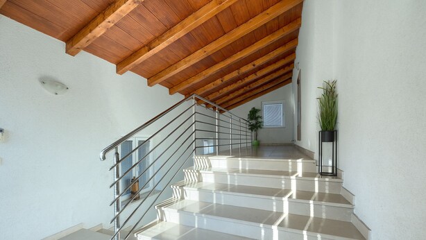 A staircase with a wooden ceiling and a metal railing, leading to a landing with a potted plant. - Villa Parlera (Ližnjan)