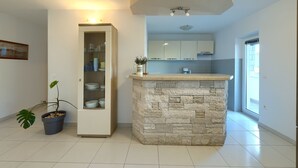 A modern kitchen with a stone island, built-in cabinets, and a potted plant. - Villa Parlera (Ližnjan)