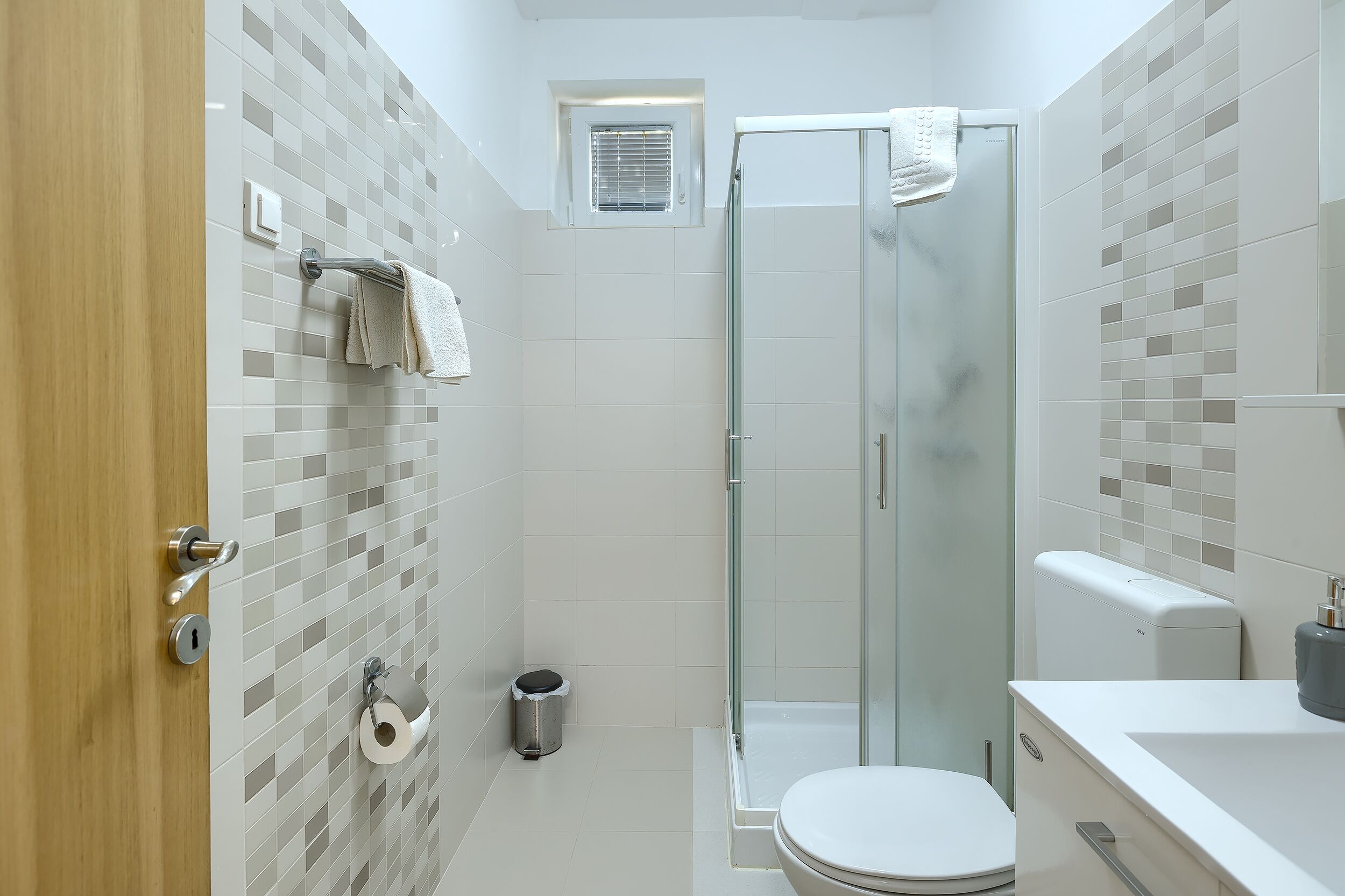 A modern bathroom with a glass shower enclosure, a toilet, and a sink.