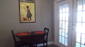 Un coin repas avec une table, des chaises et une affiche accrochée au mur.