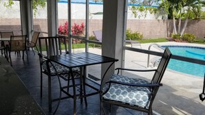 Un espace extérieur abrité comprenant une piscine, des sièges et un barbecue.