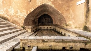 Una escalera de piedra que conduce a una entrada en arco con una reja de metal.