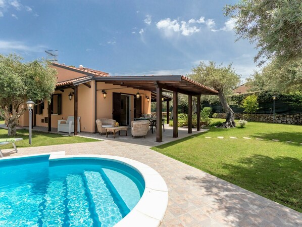 A house with a swimming pool, outdoor furniture, and a covered patio area.