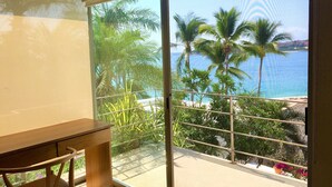 Een balkon met uitzicht op zee en palmbomen.