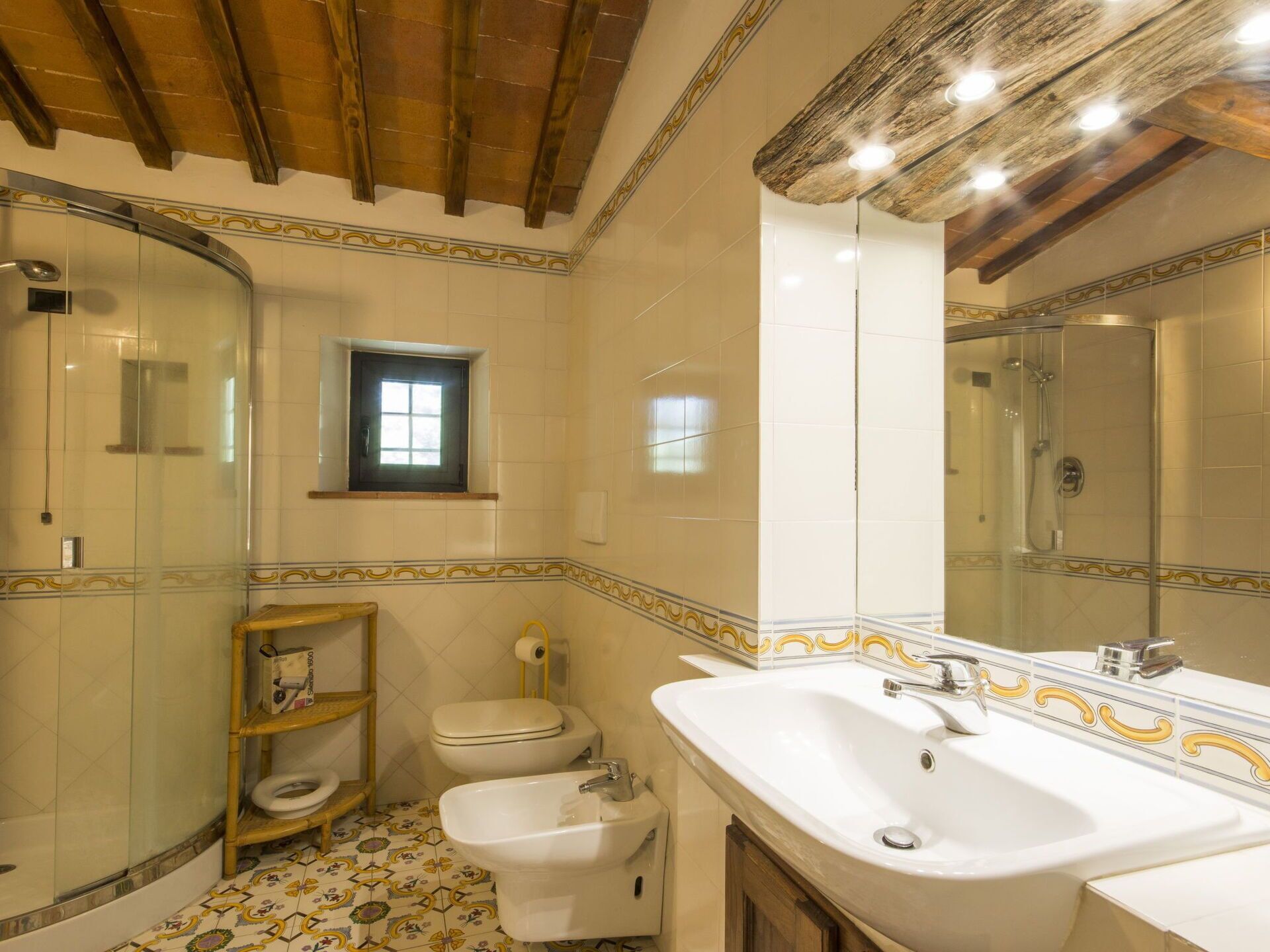 A bathroom with a shower, toilet, bidet, and a large sink with a mirror.
