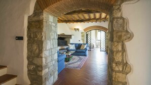 A stone archway leading to a living room with a blue sofa, a fireplace, and a view through an arched doorway. - Beautiful private villa with private pool, WIFI, A/C, TV and balcony, close to Florence (Pontassieve)