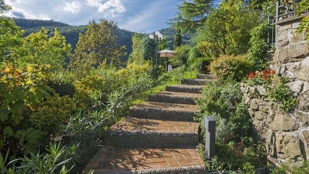 A stone staircase leading up a hill, surrounded by lush greenery and a clear sky.