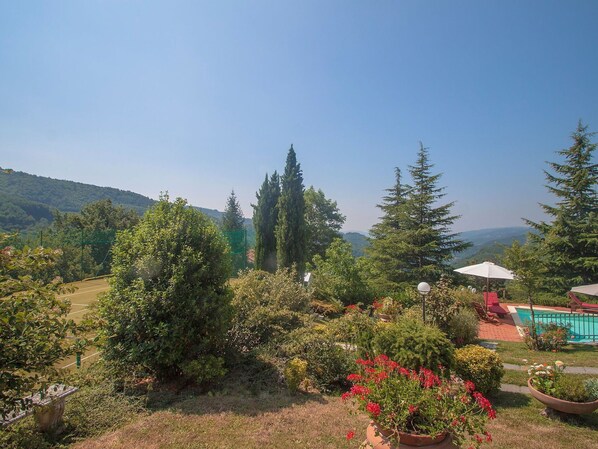 Un jardin avec une piscine, entouré d’arbres et offrant une vue sur les montagnes.