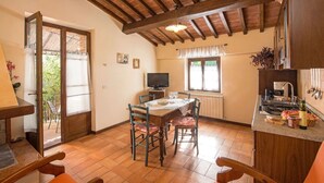 A cozy dining area with a wooden ceiling, a television, and a kitchen counter with various items. - Cosy apartment in villa for 4 guests with A/C, WIFI, pool, TV and patio (Città Della Pieve)