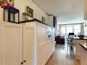 Una cocina moderna con muebles blancos, horno empotrado y un comedor con mesa y sillas.