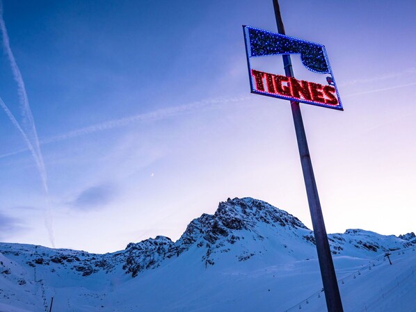 A sign with the word "TIGNES" against a snowy mountain backdrop.