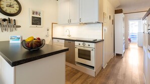 Une cuisine moderne avec des meubles blancs, un plan de travail noir et une cuisinière en acier inoxydable.