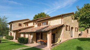 Une maison en pierre dotée d’un patio, d’un coin repas et d’un escalier menant à un deuxième étage.