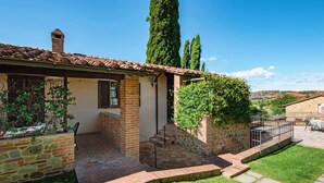 Une maison de campagne en pierre, avec un toit en tuiles, une cheminée en briques et un petit porche.