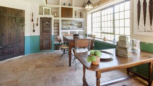 Una cocina rústica con vigas de madera, un ventanal grande y un comedor con mesa y sillas de madera.