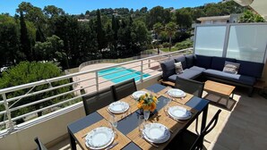 Eine Terrasse mit Pool, Sitzgelegenheiten im Freien und einem Esstisch.