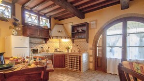 A rustic kitchen with exposed wooden beams, a tiled backsplash, and a stone archway leading to a dining area. - Nice apartment in villa with pool, WIFI, TV, terrace and pets allowed, close to San Gimignano (Poggibonsi)